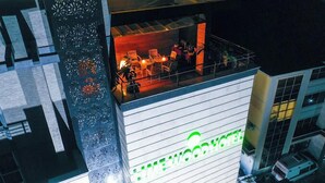 A hotel with a rooftop bar featuring outdoor seating and a view of the cityscape. - The Limewood Hotel (Port Harcourt)