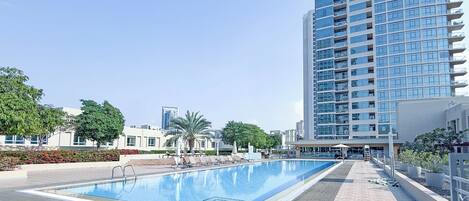 Una piscina al aire libre, sombrillas, tumbonas
