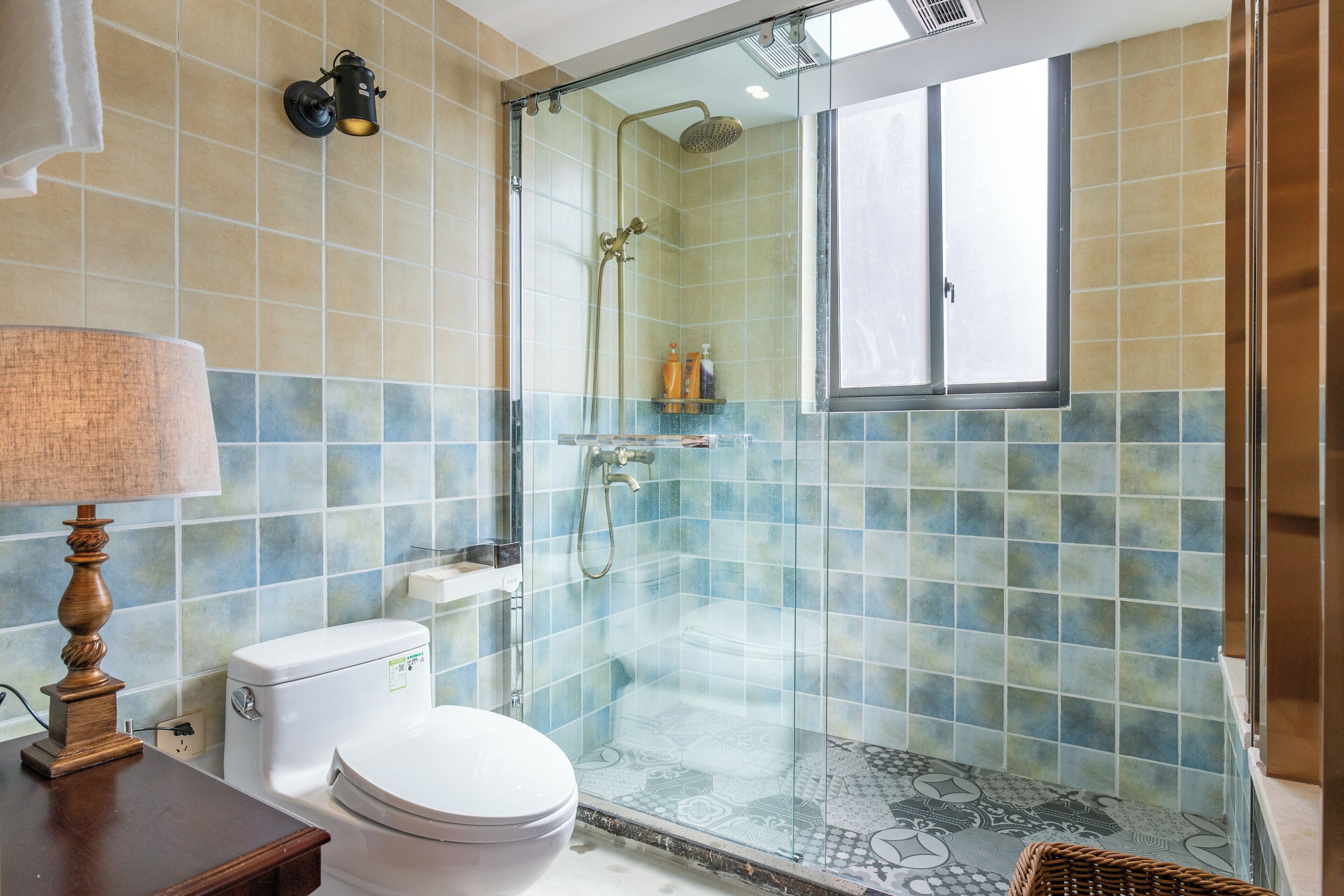 A bathroom with a toilet, a glass-enclosed shower, and a window.