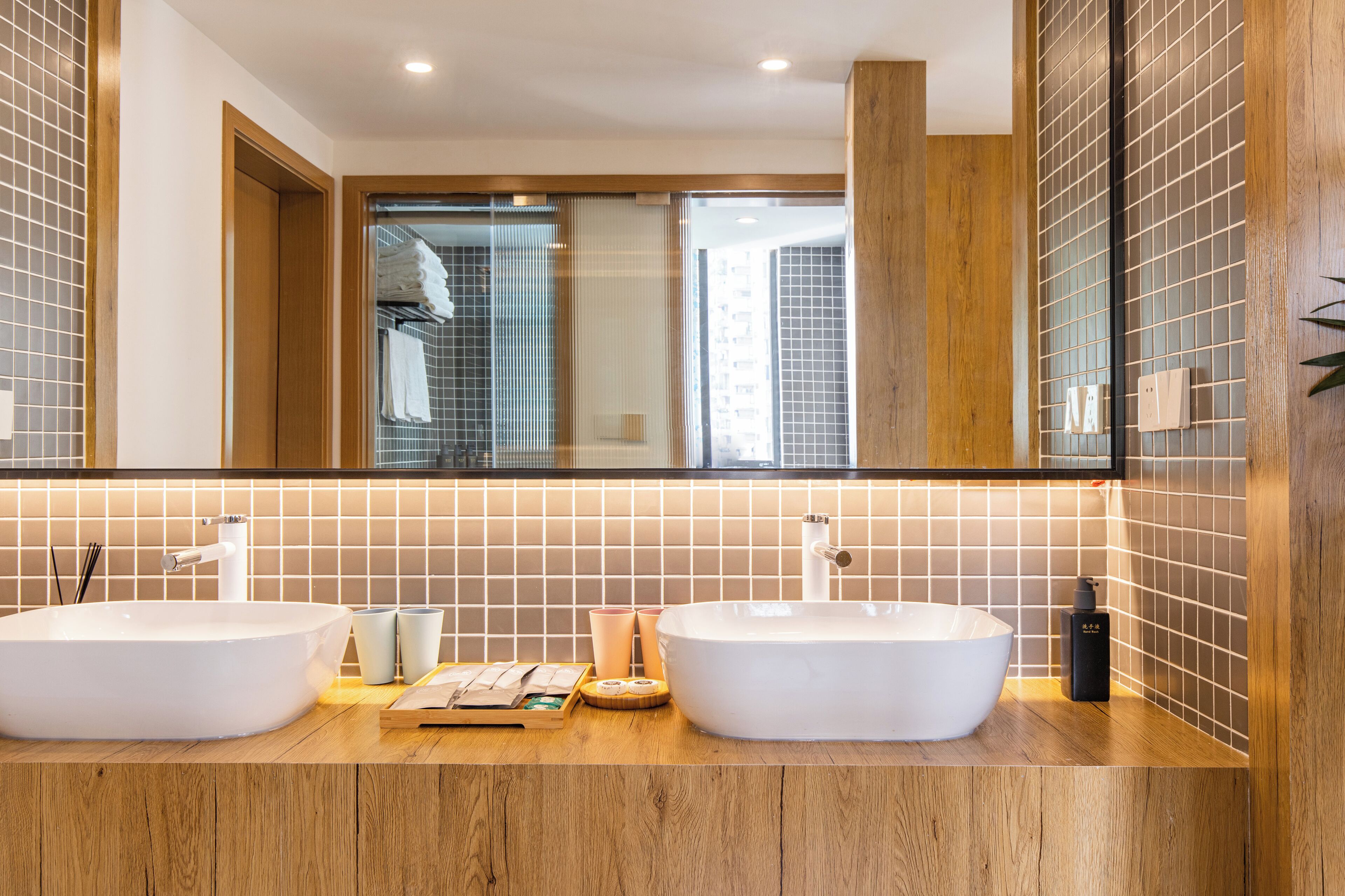 A bathroom with two large white sinks, a wooden countertop, and a mirror above.