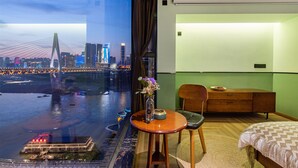 A hotel room with a large window offering a view of a city skyline and a river. -  Nuanyu Apartment with River View & Drone Show View (Chongqing)