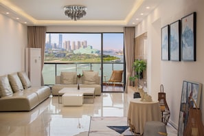 A modern living room with a sofa, coffee table, and a view of a cityscape through large windows. - Nuanyu Apartment with River View & Drone Show View (Chongqing)