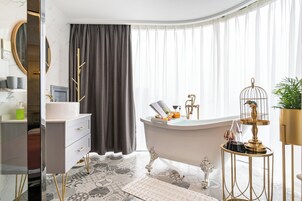 Un baño moderno con bañera, tocador y un espejo redondo.