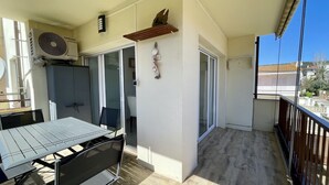 A balcony with a table and chairs, a Samsung air conditioner, decorative shells, and a view of the neighborhood.