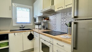 A modern kitchen with white cabinets, a built-in oven, a microwave, and a coffee maker.