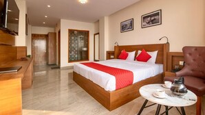 A hotel room with a wooden bed, a red and white bedspread, a coffee table with a cup and a kettle, and a TV mounted on the wall. - Shimla Inn (Shimla)