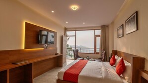 A hotel room with a large bed, a desk, a TV, and a balcony with a view. - Shimla Inn (Shimla)