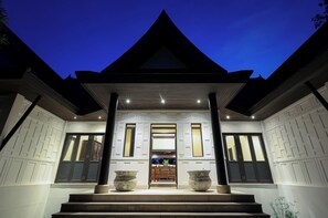 A modern building with a symmetrical facade, large windows, and a central entrance with steps leading up to it.