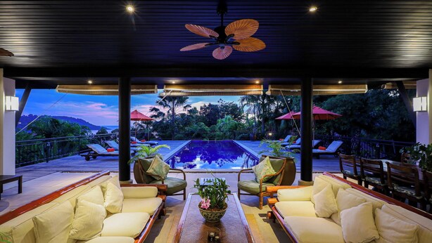 A poolside lounge with a ceiling fan, cushioned seating, and a view of a swimming pool and tropical landscape. - Katamanda villa Eden Large Villa near Kata Beach (Karon)