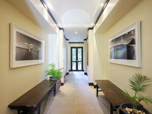 A hallway with two benches, framed artwork on the walls, and a door at the end.