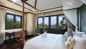 A bedroom with a large bed, a desk, and a chair. There are multiple windows providing a view of the outdoors. - Katamanda villa Eden Large Villa near Kata Beach (Karon)