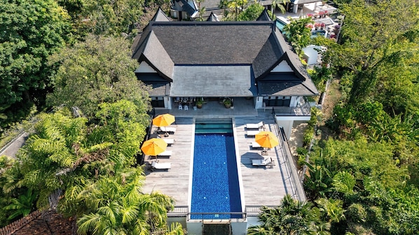 A large house with a swimming pool surrounded by lush greenery.