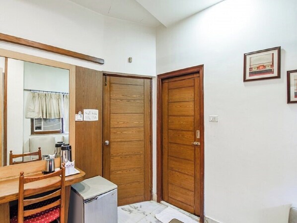 Una habitación compacta con una mesa de comedor de madera, sillas, un refrigerador pequeño y dos puertas de madera.