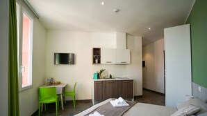 Et moderne hotelværelse med seng, skrivebord, stol og tekøkken.