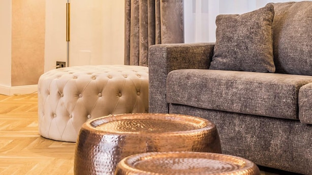 A modern living room with a sofa, ottoman, and two copper side tables.