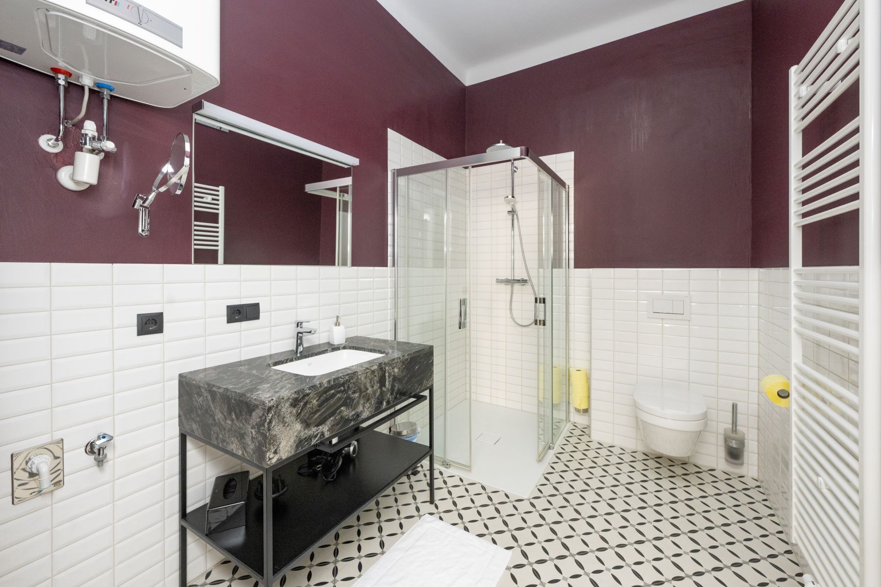 Un baño moderno con ducha de vidrio, lavamanos de mármol y paredes de azulejos blancos.