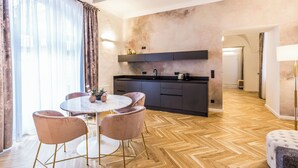 A modern kitchen with a central island, a dining area with a round table and chairs, and a herringbone wood floor.