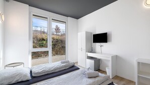 Een moderne slaapkamer met een bed, een bureau, een televisie en uitzicht door de deur.