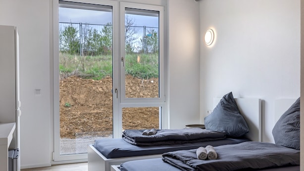 A bedroom with a bed, a bedside table, a window with a view of the outdoors, and a door leading outside. - Room '7' with Shared Terrace and Wi-Fi (Dußlingen)