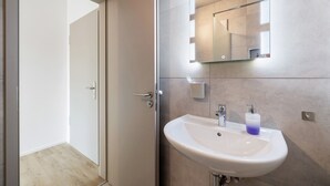 A modern bathroom with a white sink, a mirror with lights, and a door leading to another room. - Room '8' with Shared Terrace and Wi-Fi (Dußlingen)