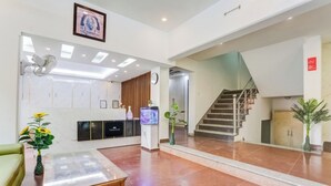 A modern lobby with a reception desk, a staircase, and a large mirror reflecting the interior. - My Home Hotels (New Delhi)