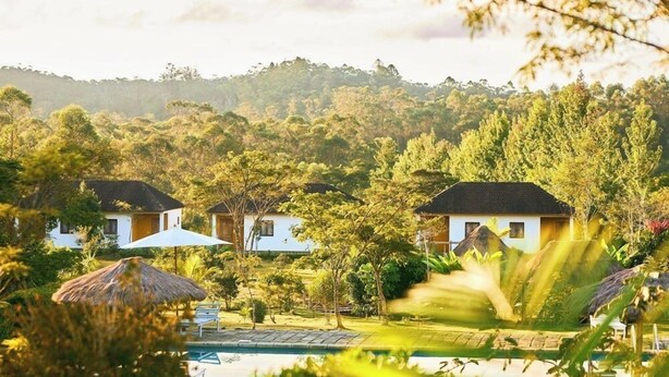Un resort con varias edificaciones blancas, una piscina y abundante vegetación.