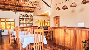 Un restaurante con mobiliario de madera, manteles blancos y lámparas colgantes.