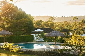 Una piscina al aire libre, sombrillas, sillones reclinables de piscina