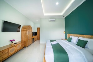 A hotel room with a bed, a TV, a wooden wardrobe, and a kitchenette.