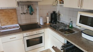 Eine Küche mit Herd, Backofen, Spüle und Mikrowelle.