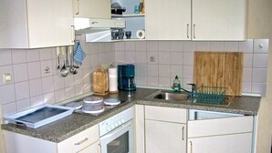 A compact kitchen with a built-in oven, a sink, and a coffee maker.