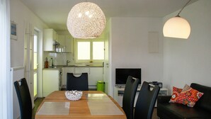 A dining area with a wooden table, black chairs, a decorative, and a TV in the background.