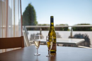 A table with a bottle and two glasses on a balcony overlooking a cityscape. - Apartment 'Apt Typ A1' with Shared Terrace, Shared Garden and Wi-Fi (Immenstaad am Bodensee)