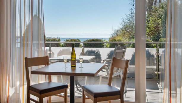 A balcony with a table, chairs, a bottle, and glasses. - Apartment 'Apt Typ A1' with Shared Terrace, Shared Garden and Wi-Fi (Immenstaad am Bodensee)