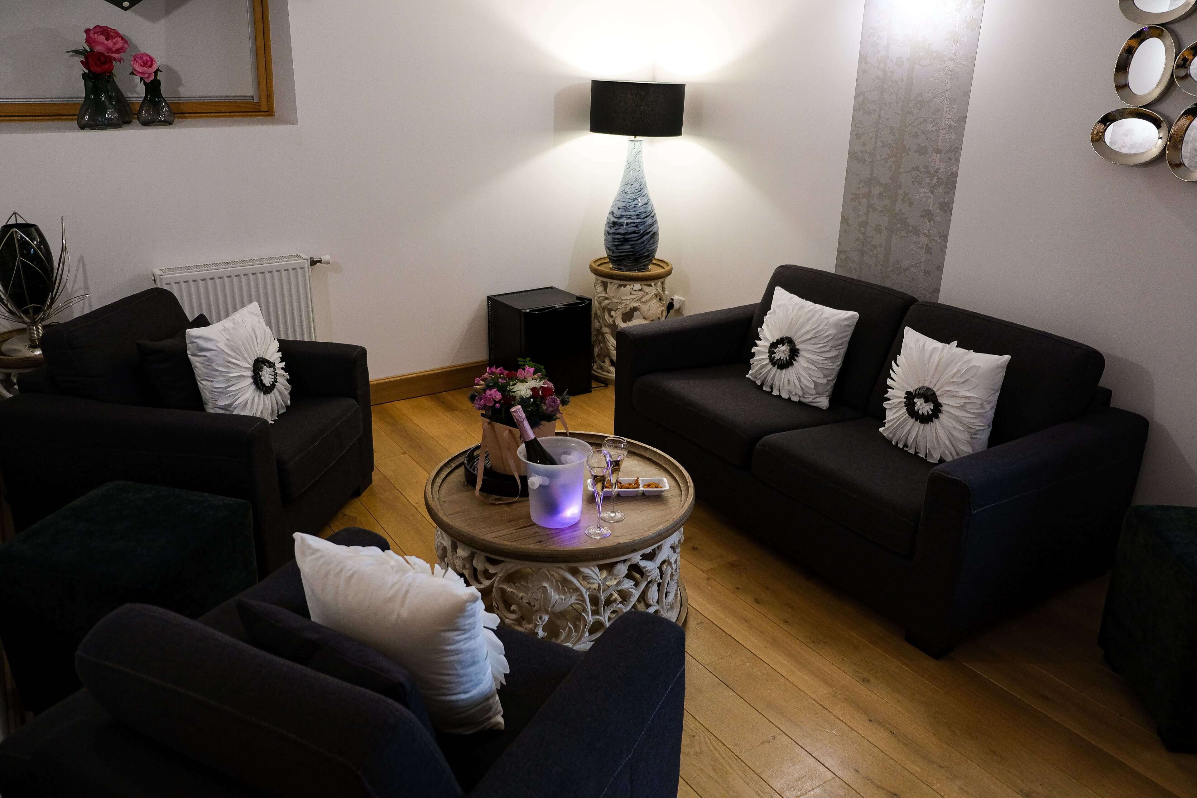 Un salon avec deux canapés, une table basse ronde, une lampe et un radiateur.