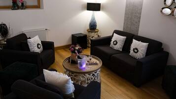 A living room with two sofas, a round coffee table, a lamp, and a radiator.