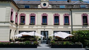 A building with a symmetrical facade, multiple windows with shutters, and a central entrance. - Le Domaine Des Fagnes (Sains-du-Nord)