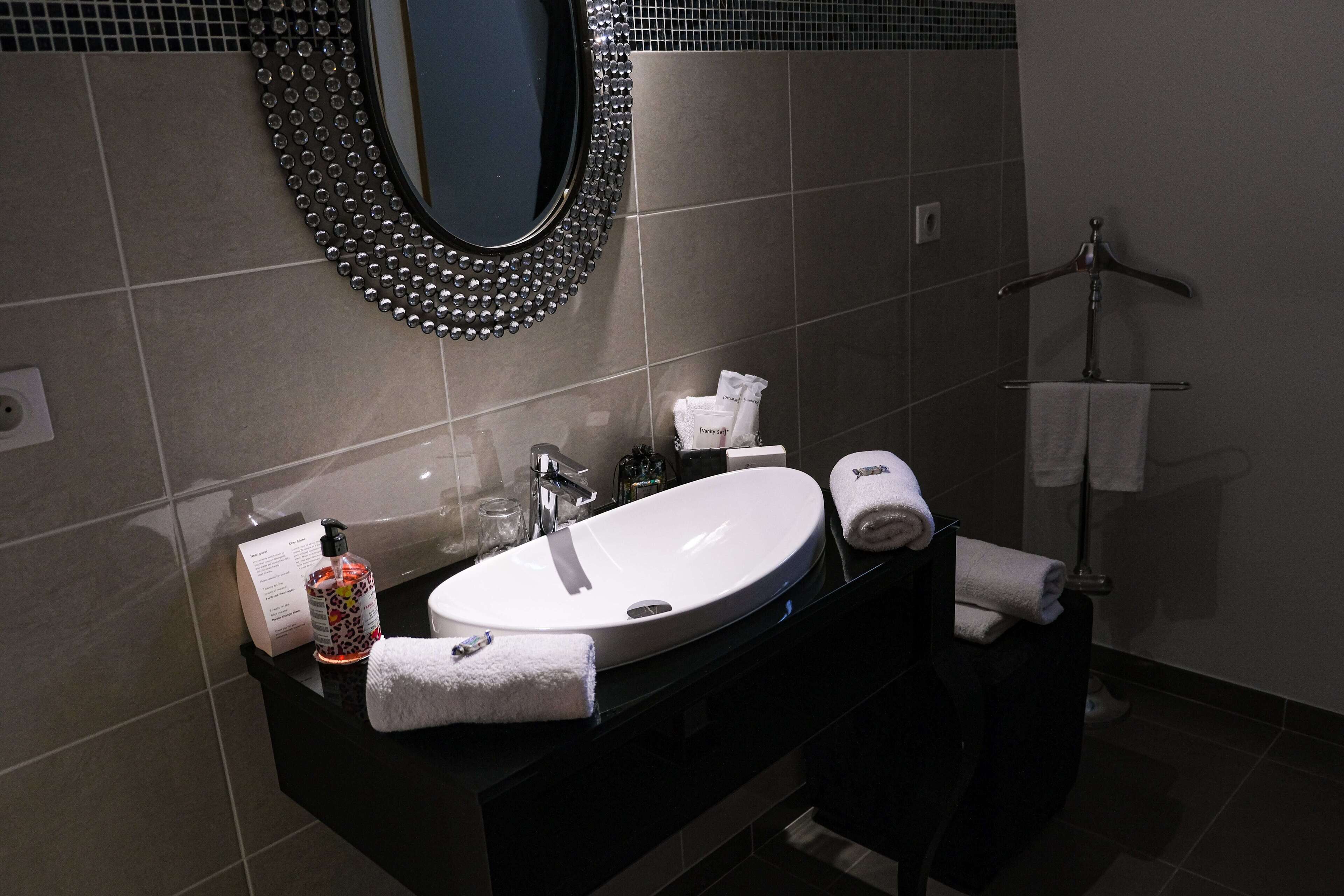 Une salle de bain moderne avec un grand miroir, un lavabo et un porte-serviettes.