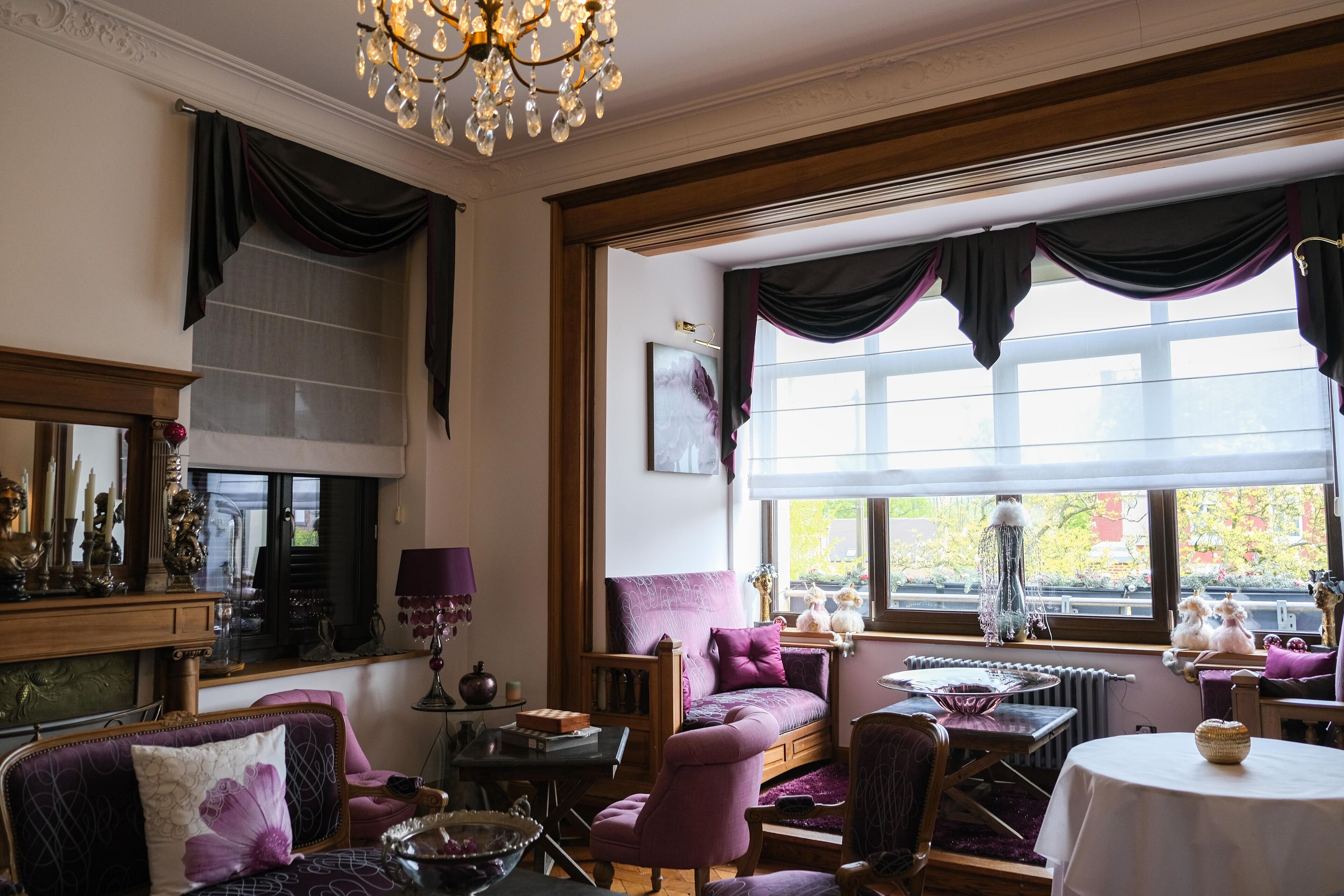 Ein gemütliches Wohnzimmer mit einer Couch, Sesseln, einem Tisch und einer Chandelüster.