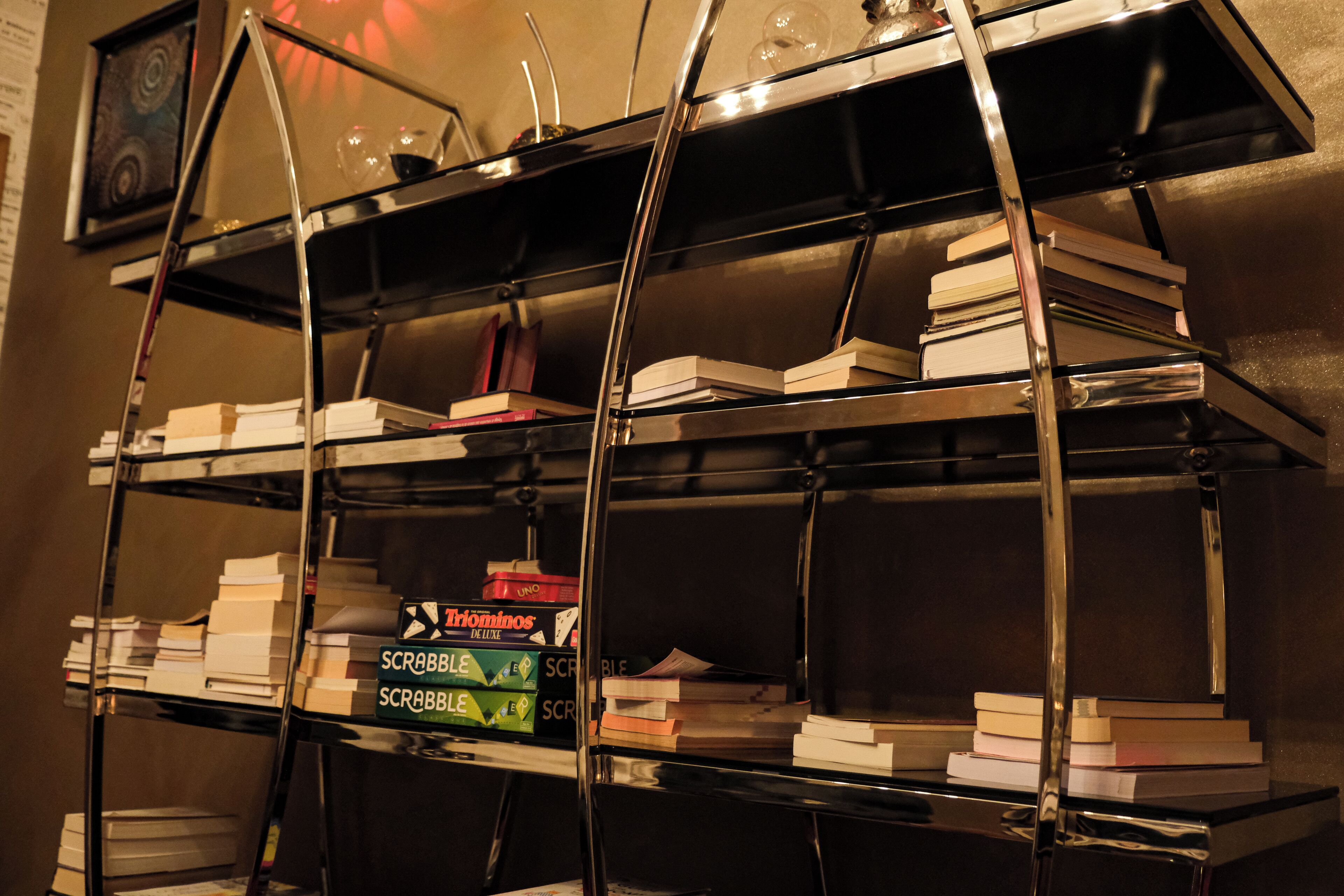 Uma estante de metal com livros e jogos de tabuleiro.