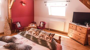 A bedroom with a bed, a wooden dresser, a television, and a window with curtains.