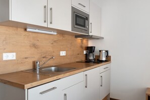 A modern kitchen with a wooden countertop, stainless steel sink, and a built-in microwave.