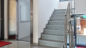 An interior view of a hotel with a staircase, elevator, and a red carpet. - Apartment 'A1' with Shared Terrace, Shared Garden and Wi-Fi (Immenstaad am Bodensee)