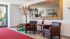 A modern lobby with two leather armchairs, a wooden-framed mirror, and a wheelchair. - Apartment 'A1' with Shared Terrace, Shared Garden and Wi-Fi (Immenstaad am Bodensee)