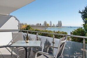 A balcony with a table and chairs, overlooking a body of water and a bridge.