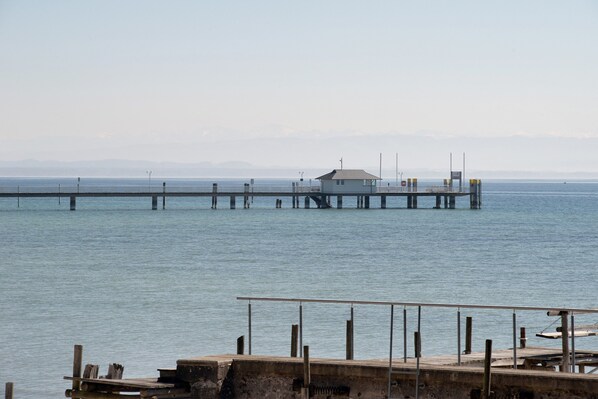 A pier extending into calm water with a small building at the end.
