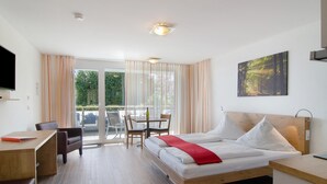 Ein Hotelzimmer mit Bett, Schreibtisch, Stuhl, Tisch und Fernseher.