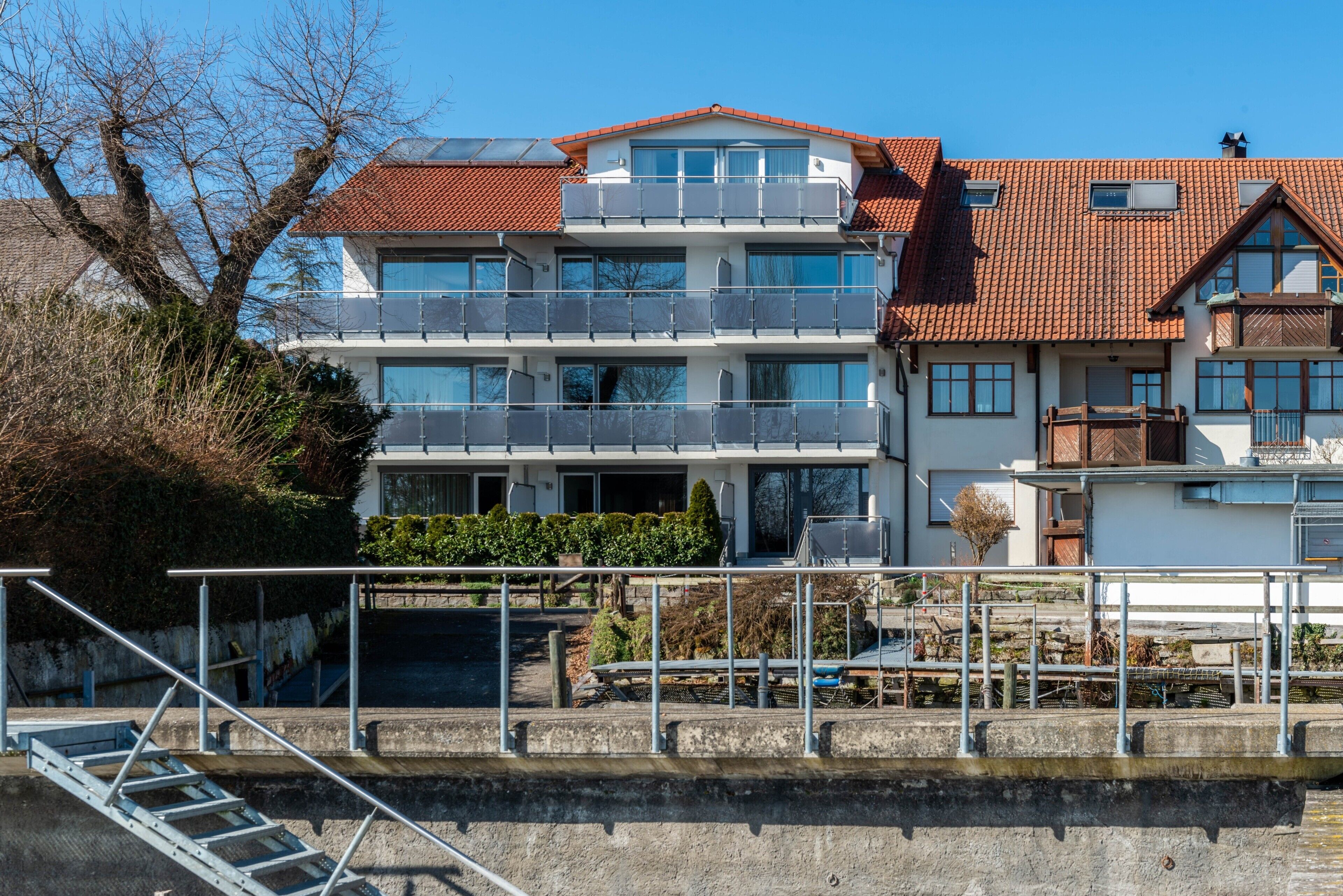 Een meerlaags gebouw met balkons, een trap en uitzicht op het water.