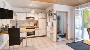 Une cuisine moderne avec un coin repas, un téléviseur et un réfrigérateur.