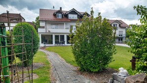 Un quartier résidentiel avec un chemin pavé, un petit jardin et une maison à deux étages dotée d’un balcon.